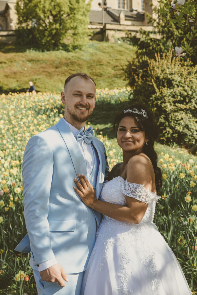 Brautpaar posiert im Sonnenschein vor bunter Blumenwiese fotograf mönchengladbach